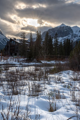 Sunset along the creek in Spring Creek, Canmore with snow, a bridge, trees, and the mountains in the foreground