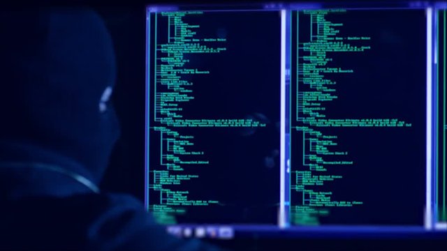 Hacker with mask breaking code. Hacker with mask using computers to crack the internet from hackers dark room. Hackers face seen from the screen.Shot on RED Cinema Camera