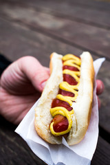 A mans hand holding  yumm hot dog