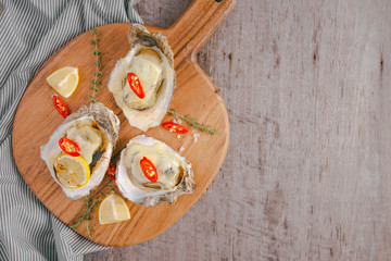 Fresh Oysters in shell with lemon on cutting board
