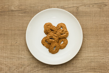 Cookies with a hole, sweet temptation. Dessert on white dish and wooden table.  Overhead, flat lay of candy.
