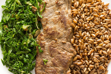 Rye, steak and cabbage meal on white plate. Overhead close up of food dish.