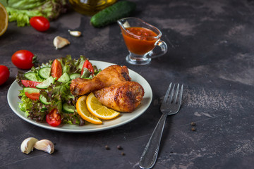 Fried chicken legs and fresh salad on a dark background