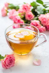 Cup of tea and tender pink roses on a white background