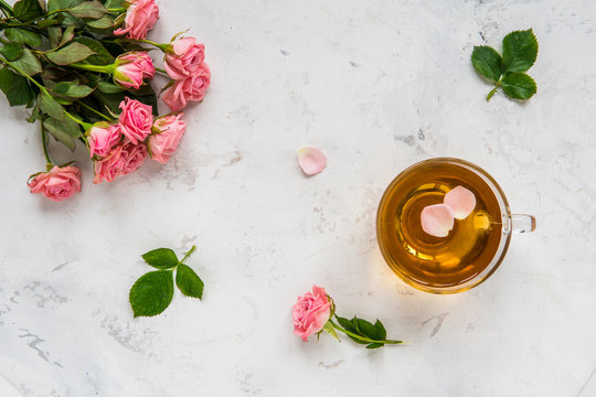 Cup of tea and tender pink roses on a white background copy space
