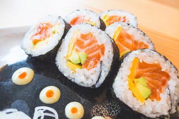 Closeup of sushi roll with salmon and avocado on plate