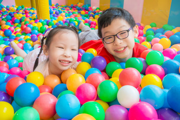 Asian boy and girl smiling while playing at indoors playground