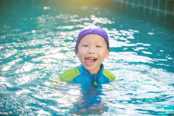 Fototapeta na wymiar Little asian girl in swimming suit smiling in swimming pool