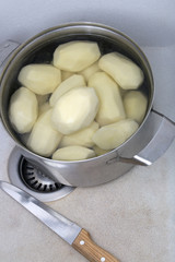 Peeled potatoes in a saucepan in a kitchen sink