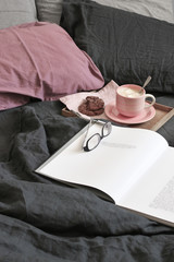 Breakfast in tray and open book with glasses in bed