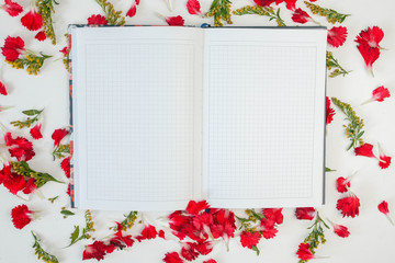 Open diary in the petals of flowers on a white background