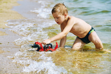 The boy plays with toys at sea . Cheerful child on a sea holiday