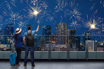 Fototapeta na wymiar Traveler asian couple standing on terrace and watch the fireworks