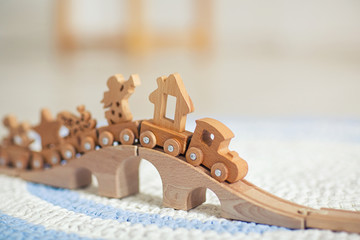 Wooden toy train on railroad with wooden bridge on the floor of a children's room. close up