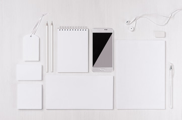 White blank stationery as work place with phone, earphone on light white wood background. Branding mock up for branding, graphic designers presentations and business portfolios. 