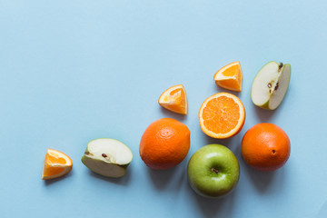 Fresh oranges and green apples on the blue background