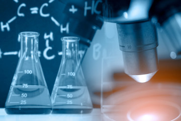 Microscope with lab glassware, science research and development concept 