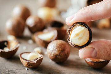 Closeup view of fingers holding Macadamia nut. Healthy food - obrazy, fototapety, plakaty