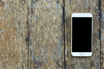 Smartphone on old wood desk on top view.