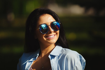 Brunette with dazzling smile in sunglasses looking at the sun.