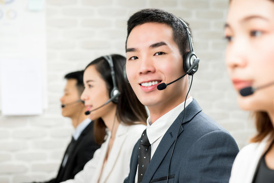 Smiling male Asian customer service telemarketing agent in call center