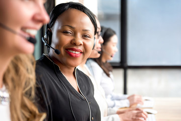 Friendly black woman wearing microphone headset working in call center