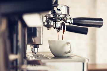 Coffee maker machine brewing espresso into the cup