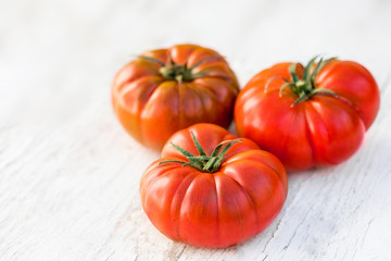 Tomatoes on bright wooden background with copy space. Fresh ripe organic tomatoes on rustic white wood table, top view.