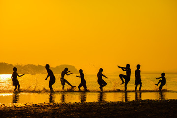 group of happy child playing water on sunset.