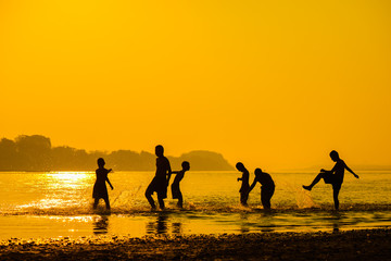 group of happy child playing water on sunset.