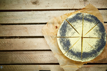 sliced mousse cake with yellow glaze and poppy seeds on the wooden background