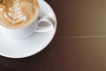 Cup of coffee with latte art on wooden table background