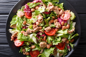 Delicious salad of tuna, borlotti beans, tomatoes, lettuce close-up on a plate. horizontal top view