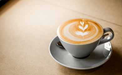 cup of coffee with heart pattern in a white cup on wooden background