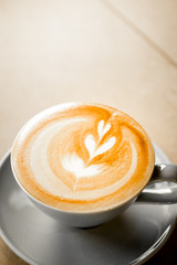 cup of coffee with heart pattern in a white cup on wooden background