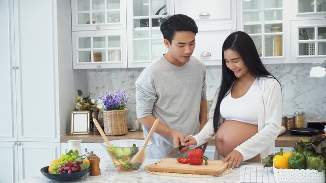 Young husband help pregnant wife cooking