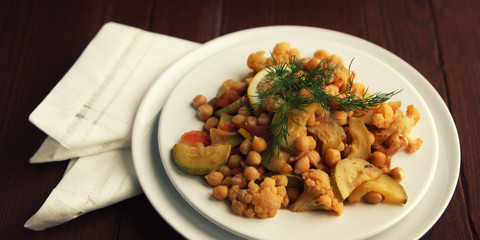 Vegetable stew with chickpeas, cauliflower and cabbages. Organic food. Vegan dish. European cuisine. Vegetarian lunch. Wide photo. Close up.