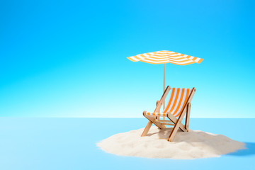 The concept of a tropical vacation. A chaise longue under an umbrella on the sandy island. Sky with copy space