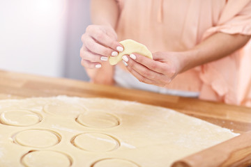 Young woman trying to make pierogi in kitchen