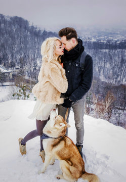Beautiful couple hugging on snow-covered mountain