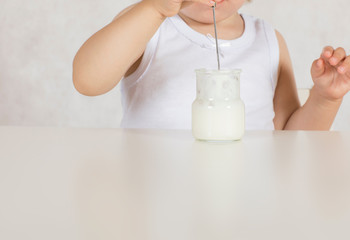 Small girl eats natural sugar free yogurt. Closeup