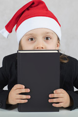 Boy in Santa's hat and black classical jacket. , Boy in Santa's hat and black book.