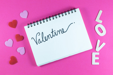 Valentine's day love letter with notebook on pink paper background with copy space.