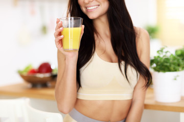 Fit smiling young woman with healthy juice in modern kitchen