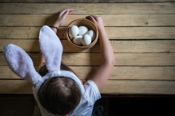 Fototapeta premium the child prepares for Easter, paints eggs in the ears of a rabbit