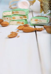 Fototapeta na wymiar Almond turron covered by pistachio chocolate on a wooden surface.