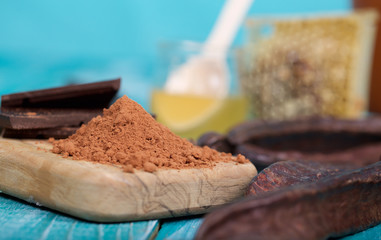 Carob pods and powder on a wooden surface.