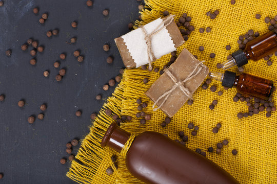Cubeb pepper grains, soap, and cubeb essential oil on a wooden surface.