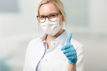 Fototapeta na wymiar Ärztin mit medizinischen Handschuhen und Mundschutz zeigt Daumen hoch