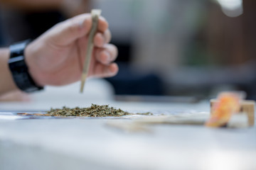 Heap of cannabis And the blur of the man's hand is rolling the cannabis with a shallow depth of field